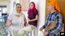 Navneet Kaur, left, a volunteer interpreter with Innovation Law Lab, hands out towels and toiletries to Carlos Marroquin, right, after he was released from a nearby federal prison at the Dasmesh Darbar Sikh temple in Salem, Oregon, Oct. 3, 2018.