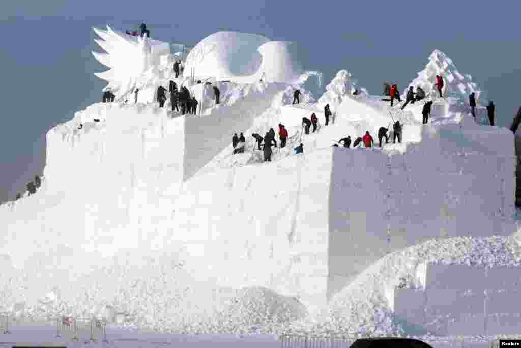 People prepare a snow sculpture for the Harbin Sun Island International Snow Sculpture Art Expo in Harbin, Heilongjiang province, China.