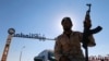 FILE - A member of Libyan forces loyal to eastern commander Khalifa Haftar holds a weapon as he sits on a car in front of the gate at Zueitina oil terminal in Zueitina, west of Benghazi, Libya, Sept. 14, 2016. 