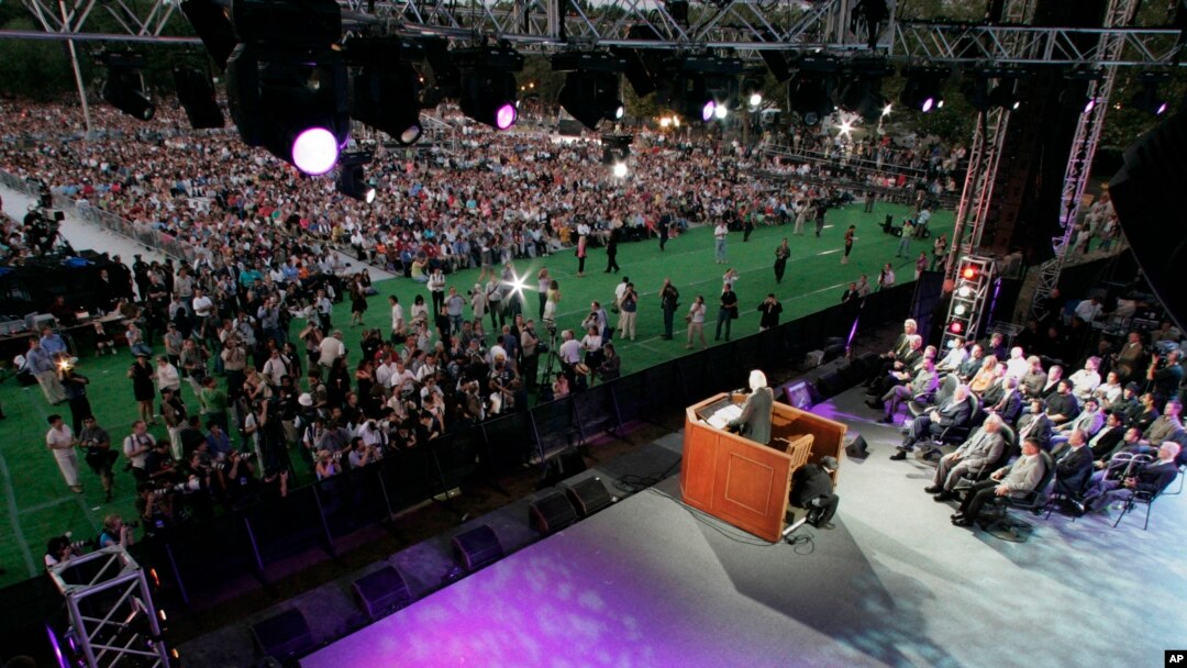 Photographers and spectators approach the stage as Rev. Billy Graham preaches on the first night of his three-day crusade at Flushing Meadows Corona Park in the Queens borough of New York Friday, June 24, 2005. (AP Photo/Julie Jacobson)