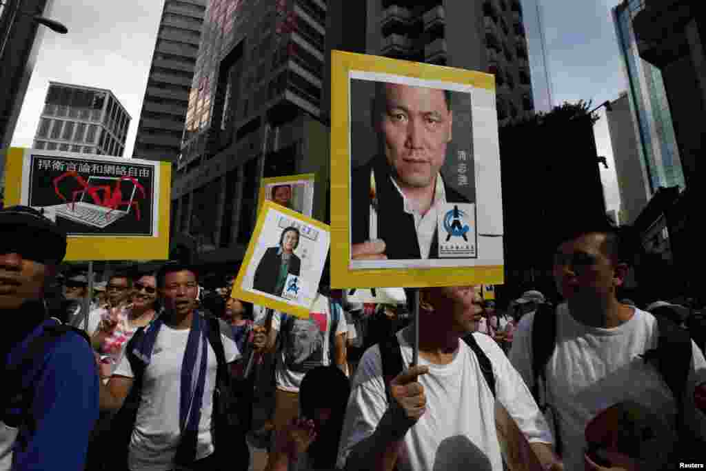 Demokratik islohotlar o'tkazilishini talab qilgan namoyishchilar hibsdagi xitoylik inson huquqlari faoli Pu Zikiang (o'ngda) va jurnalist Gao Yuning suratlarini ko'tarib chiqishdi, 1-iyul, 2014-yil.