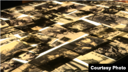 Hundreds copies of photographs of Jewish life under Nazi persecution, scattered on a lighted table at Yad Vashem's "Flashes of Memory" exhibition in Jerusalem, January 24, 2018.