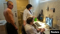 A man (L) is x-rayed to detect tuberculosis during a medical examination, Jan. 29, 2013.