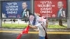 FILE - A supporter of the presidential candidate of Turkey's main opposition Republican People's Party Muharrem Ince waves flags as she walks past election campaign posters for Turkish President Recep Tayyip Erdogan, during an election rally in Ankara, June 22, 2018.