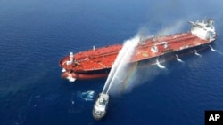 An Iranian navy boat sprays water to extinguish a fire on an oil tanker in the sea of Oman, Thursday, June 13, 2019.