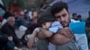 FILE - A Syrian refugee child sleeps on his father's arms while waiting to board a bus, after arriving on a dinghy from the Turkish coast to the northeastern Greek island of Lesbos, Oct. 4 , 2015.
