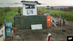 Displaced South Sudanese next to United Nations peacekeepers from Mongolia guarding the gate, at a makeshift camp at the United Nations Mission in South Sudan (UNMISS) base in the town of Bentiu, South Sudan, Sept. 22, 2014. 