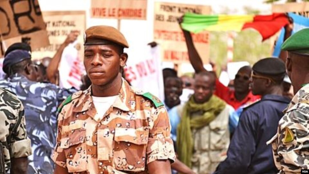A national guard soldier walks by demonstrators at Bamako airport, Mali. (VOA - N. Palus)