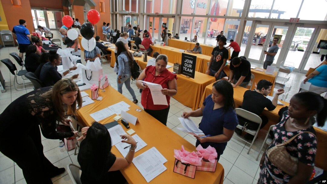 FILE - People attend a job fair at Dolphin Mall in Miami. 
