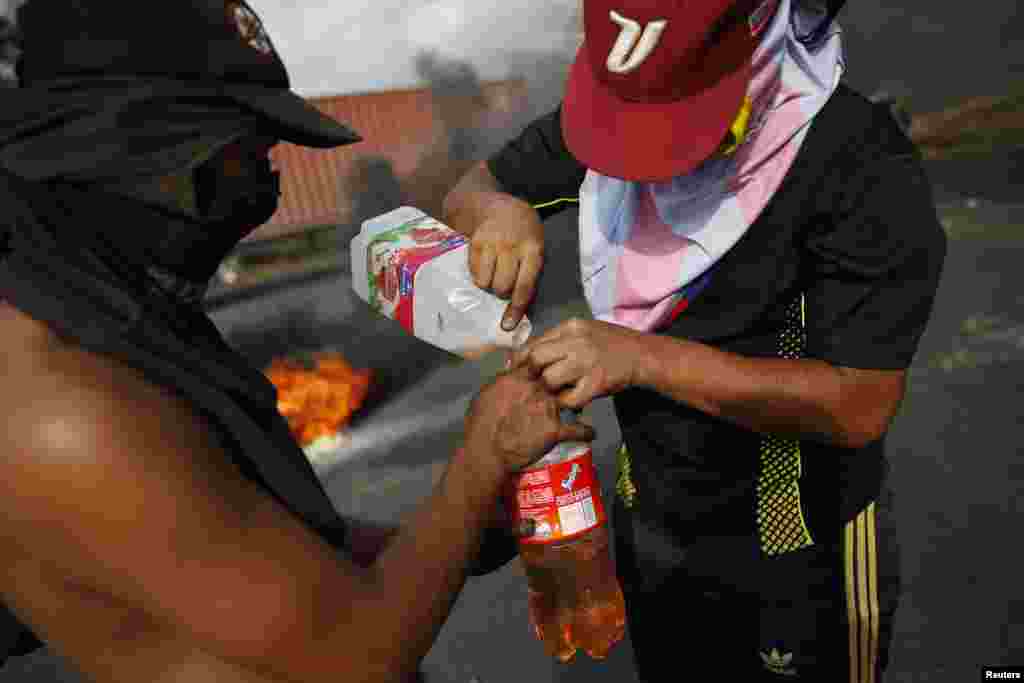 Manifestantes enchem uma garrafa com gasolina durante os protestos contra Nicolás Maduro em San Cristobal, cerca de 660 km a sudoeste de Caracas, Fev. 26, 2014. 