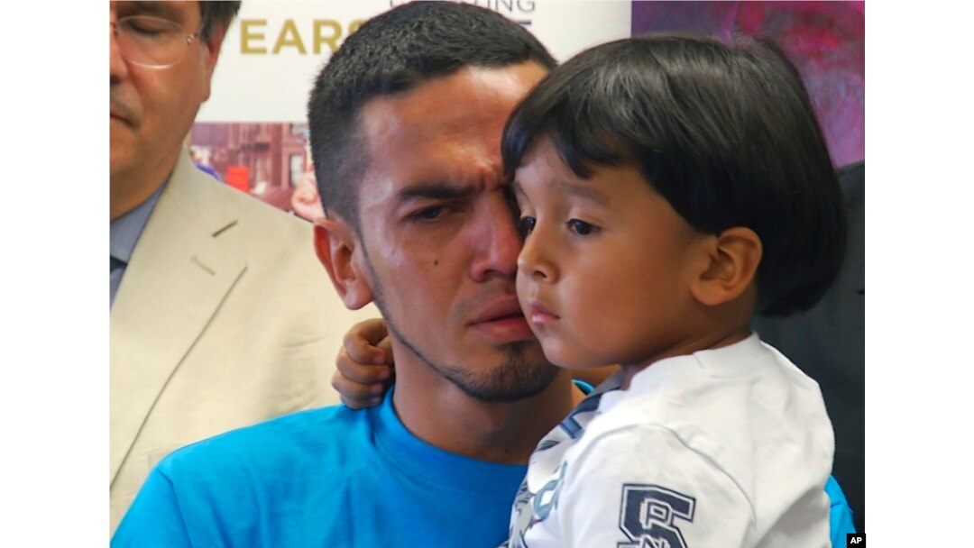 Javier Garrido Martinez holds his 4-year-old son during a news conference in New York, Wednesday, July 11, 2018.