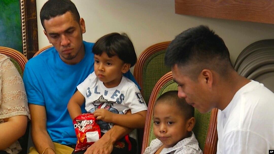 In this image taken from video, Javier Garrido Martinez, left and Alan Garcia, right, sit with their 4-year-sons at a news conference in New York, Wednesday, July 11, 2018. They men were reunited with their children after almost two months of separation, Authorities took their boys them when they stopped at the U.S. southern border. (AP Photo/Robert Bumsted)