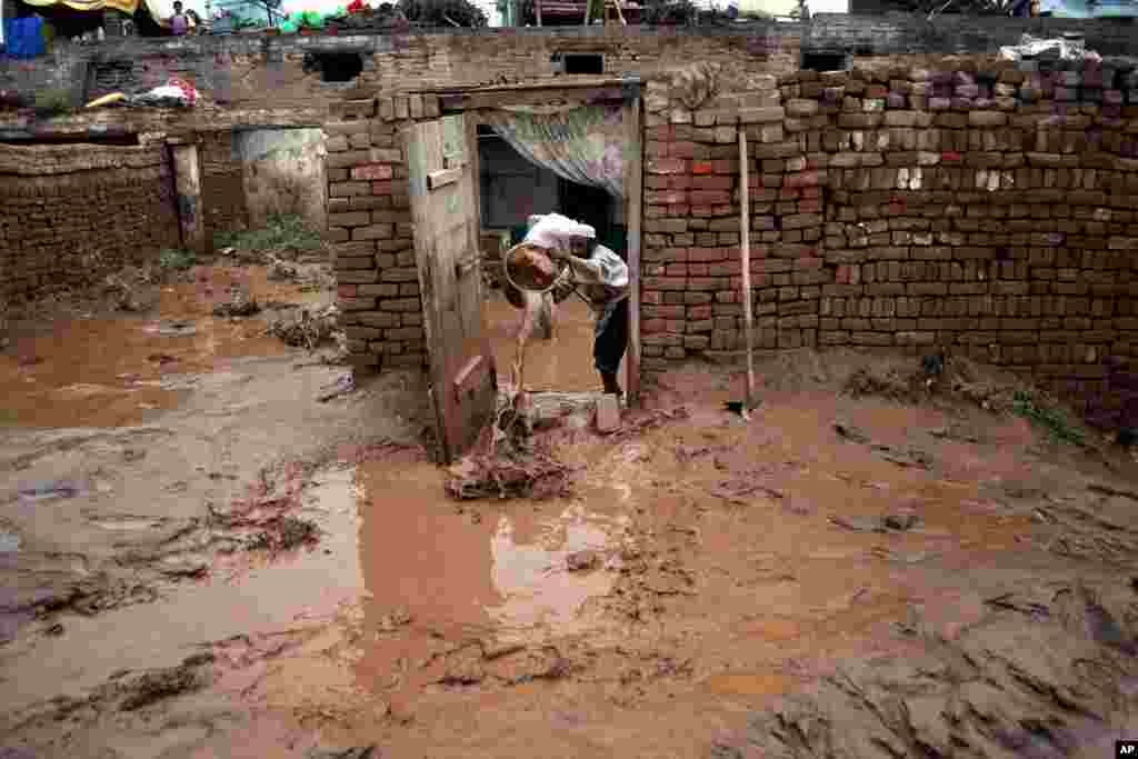 A Pakistani empties a bucket of muddy water from his home flooded by heavy rains in Peshawar, Pakistan, August 3, 2013. 