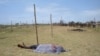 FILE - The lifeless body of a man is covered with a shroud as it lies in an open field in Kismayo, Somalia. Inter-clan violence killed six people Saturday in Labi-Aano village, 45 km east of Dhuusamareeb, Somalia. 