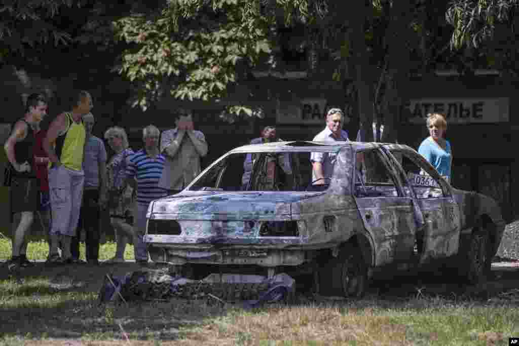 People look at a car following shelling from Ukrainian government forces, Slovyansk, Ukraine, May 28, 2014.