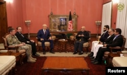 FILE - Afghanistan's President Ashraf Ghani, right in backgroud, and U.S. special envoy for peace in Afghanistan, Zalmay Khalilzad, left in background, meet in Kabul, Nov.10, 2018.