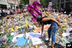 FILE - A young woman views of flower tributes for the victims of the explosion at St. Ann's square in central Manchester, England, May 25, 2017.
