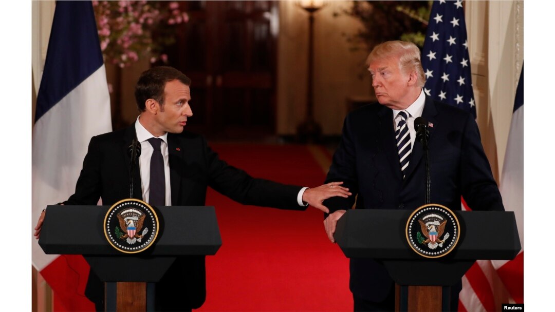 French President Emmanuel Macron reaches out to U.S. President Donald Trump as he speaks during their joint news conference at the White House in Washington, April 24, 2018.