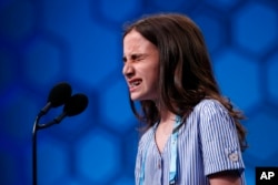 Caroline Kovacs, 10, of Hoboken, N.J., reacts as she spells out a word in the third round of the Scripps National Spelling Bee, May 29, 2019, in Oxon Hill, Md.