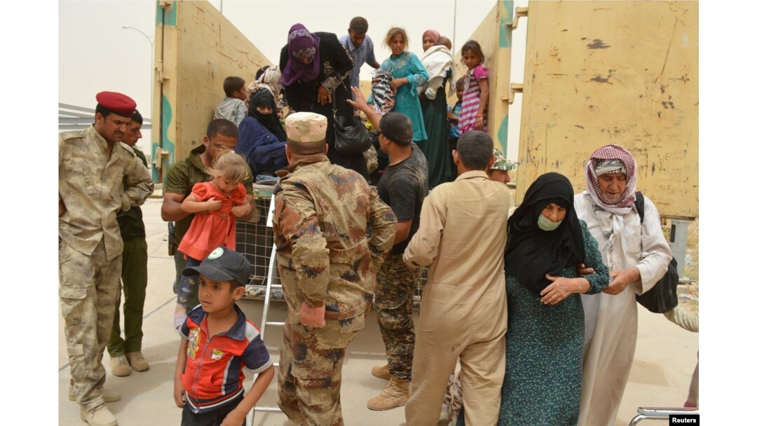 Iraqi soldiers help civilians, who fled from Falluja because of Islamic State violence, during a dust storm on the outskirts of Fallujah, Iraq, June 18, 2016