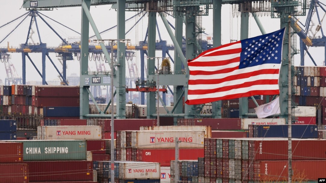FILE - Chinese shipping containers are stored beside a U.S. flag after they were unloaded at the Port of Los Angeles in Long Beach, California, on May 14, 2019. 