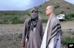 FILE - In this image taken from video obtained from Voice of Jihad website on June 4, 2014, Sgt. Bowe Bergdahl, right, stands with a Taliban fighter in eastern Afghanistan.