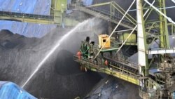 FILE - Water is sprayed onto a shipment of coal after being unloaded from a cargo vessel at the Mormugao Port Trust in Goa, India, March 11, 2021.