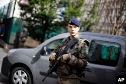 FILE - A French soldier stands near the scene where soldiers were hit and injured by a vehicle in the western Paris suburb of Levallois-Perret near Paris, France, Aug. 9, 2017.