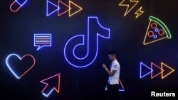 资料照：一名男子手持手持走过TikTok的标识。（2019年10月18日）
