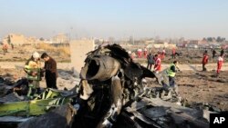 FILE - Debris is seen from a Ukrainian airliner accidentally downed by Iran, as authorities work at the scene in Shahedshahr, near Tehran, Iran, Jan. 8, 2020. 