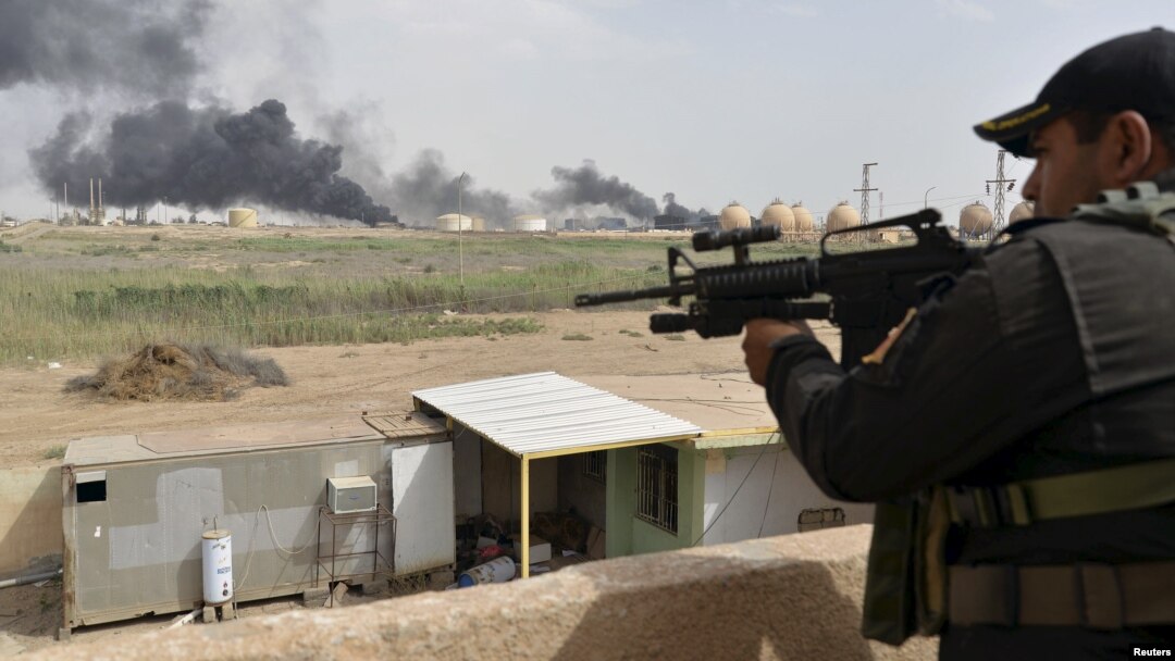 FILE - A member from the Iraqi security forces guards as smoke rises from Baiji oil refinery, north of Baghdad, Iraq May 26, 2015.