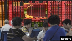 Investors play cards in front of an electronic board showing stock information at a brokerage house in Shanghai, China, Sept. 9, 2015. 