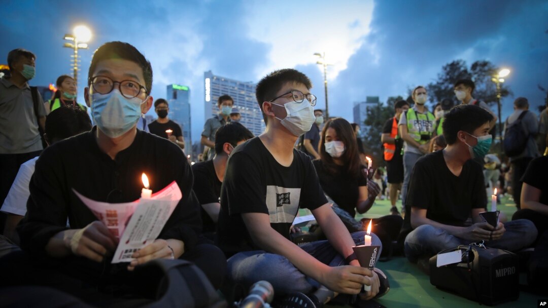 Hong Kong democracy activist Joshua Wong, center, holds a candle as he joins others for a vigil to remember the victims of the 1989 Tiananmen Square Massacre at Victoria Park in Causeway Bay, Hong Kong, June 4,2020. 