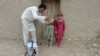 FILE - An Afghan health worker administers polio vaccine to a child during a campaign at a refugee camp on the outskirts of Jalalabad in Nangarhar province on May 11, 2015.