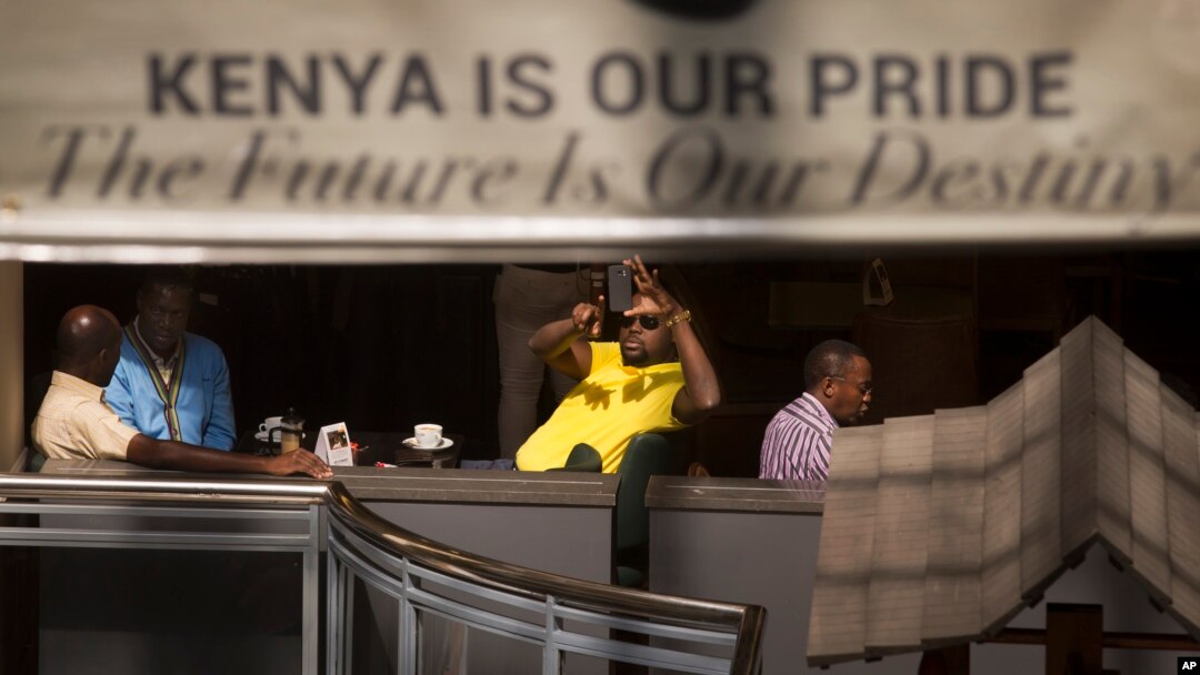 A man takes photographs of the mall with his smartphone while he sits in a cafe at the reopened Westgate Shopping Mall in Nairobi July 18, 2015. (AP Photo/Ben Curtis)