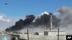 Suriyaning Hims viloyati Talbisa shahrida Rossiya bergan havo zarbalaridan so'ng quyuq tutun ko'tarilmoqda, 30-sentabr, 2015-yil.