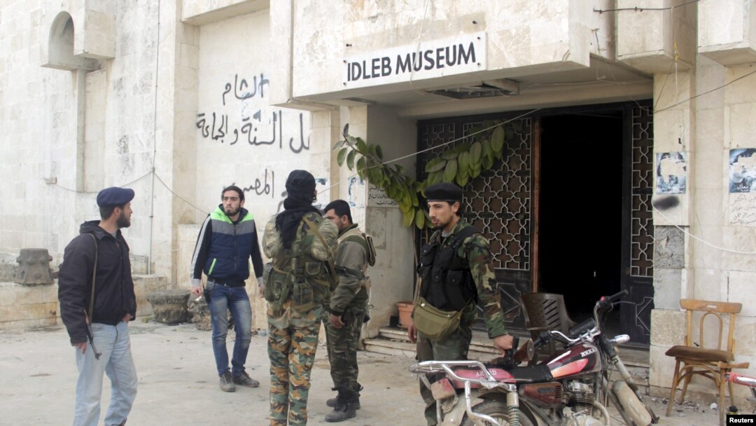 FILE - Rebel fighters stand outside Idlib museum in Idlib, Syria, after Islamist rebel fighters took control of the area, April 1, 2015. 