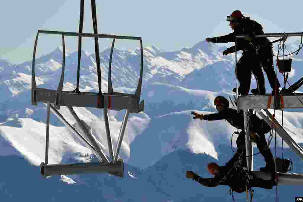 Technicians reach out to catch a piece of a metal structure during the installation of a 12-meter-long platform at the top of the Pic du Midi, one of France's tallest mountains, in Bagneres-de-Bigorre.