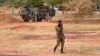 A Burkinabe soldier walks past a French Armoured Personnel Carrier part of a French military convoy heading to Niger, stopped by protesters in Kaya, Burkina Faso, Nov. 20, 2021.