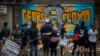 FILE - People gather at a memorial featuring a mural of George Floyd, near the spot where he died while in police custody, in Minneapolis, Minnesota, May 31, 2020.