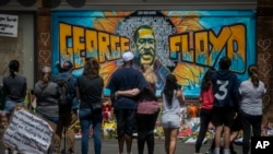 FILE - People gather at a memorial featuring a mural of George Floyd, near the spot where he died while in police custody, in Minneapolis, Minnesota, May 31, 2020.