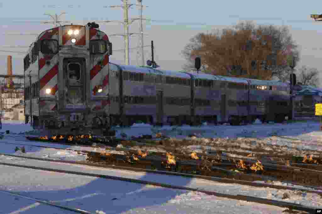 A Metra train moves southbound to downtown Chicago as the gas-fired heater on the rails keeps the ice and snow off the switches near Metra Western Avenue station in Chicago, Illinois. Forecasters warn that the freezing weather will get worse and could be life-threatening.