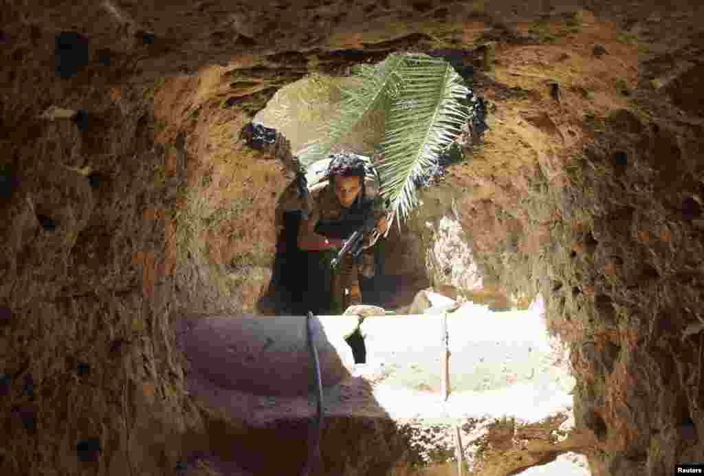 A Free Syrian Army fighter moves through a tunnel to take cover from snipers loyal to Syria's President Bashar al-Assad in Deir al-Zor, July 14, 2013.