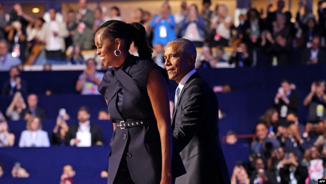 Former US President Barack Obama (L) greets Former US First Lady Michelle Obama on the second day of the Democratic National Convention (DNC) at the United Center in Chicago, Illinois, on August 20, 2024.