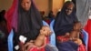 Malnourished babies are held by their mothers, both of whom fled the drought in southern Somalia, at a feeding center in a camp in Mogadishu, Somalia, Feb. 25, 2017.