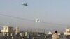 Afghan security forces keep watch as a NATO helicopter flies over at the site of an attack in Jalalabad December 2, 2012. Suicide attackers detonated bombs and fired rockets outside a major U.S. base in Afghanistan on Sunday, killing five people in a braz