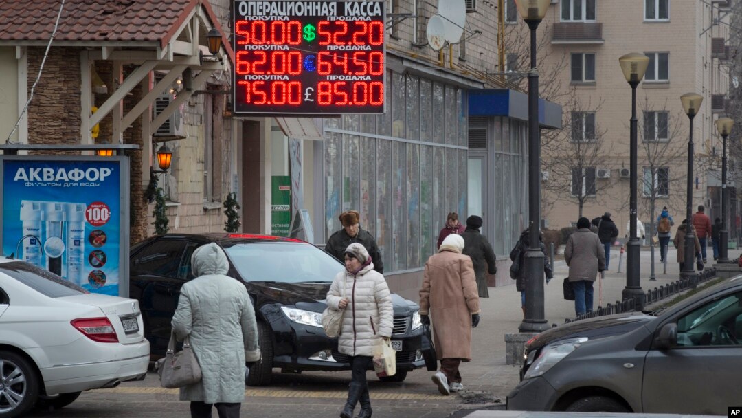 People walk past a currency exchange rate display in central Moscow, Dec. 1, 2014.
