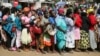 FILE - Women queue for a planned distribution of food for those suffering from the impact of the coronavirus pandemic, at a site in the Kibera slum of Nairobi, Kenya, April 10, 2020.