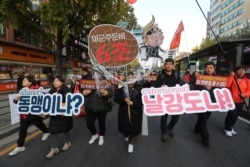 FILE - Protesters march to oppose the United States' demand for raising costs to station U.S. troops in South Korea, in Seoul, Nov. 16, 2019.