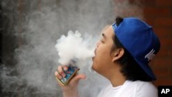 A man, who declined to be identified, puffs out a vapor cloud while smoking an electronic cigarette during a work break Dec. 11, 2019, in Tukwila, Wash.